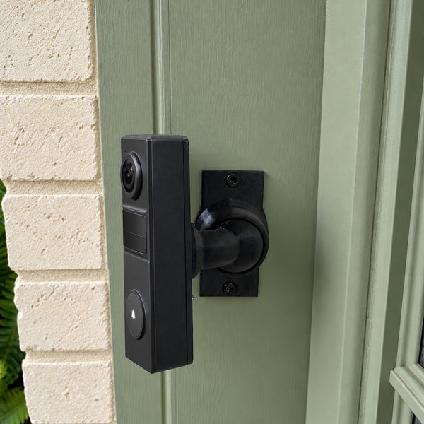 Tapo D205 on adjustable 15–90 degree swivel mount, left-facing view on sage green painted wood trim beside cream brick